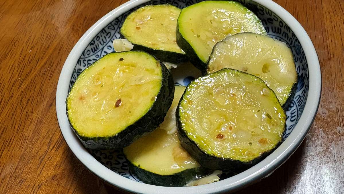 2026年5月31日夜、初収穫したズッキーニを輪切りにし、チーズを溶かして焼いた家庭料理。皮も実も柔らかく、つやつやのままうつわに盛られている。