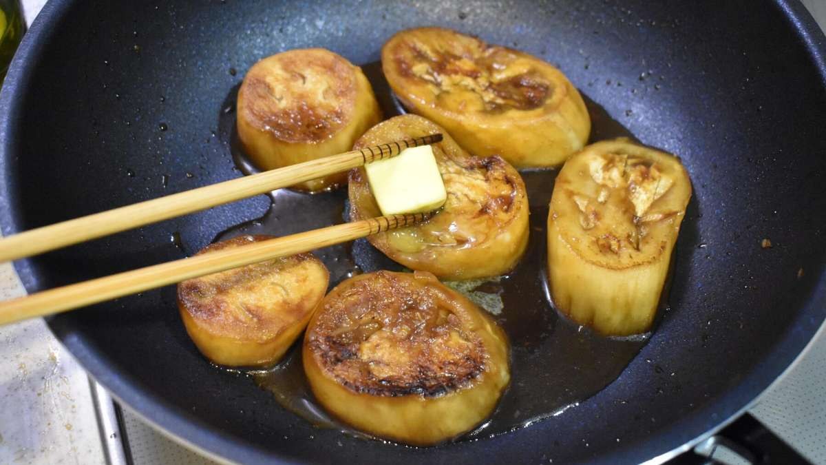 フライパンで輪切りにした白なすをバターで焼いている様子。表面はきつね色、中心の切り口にバターが溶けている